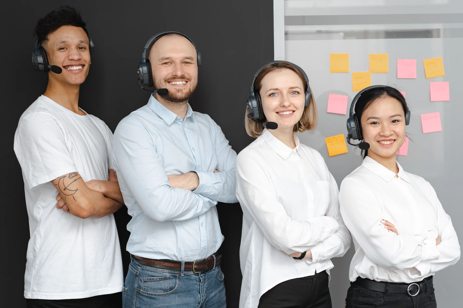 Friendly customer support team standing together with headsets