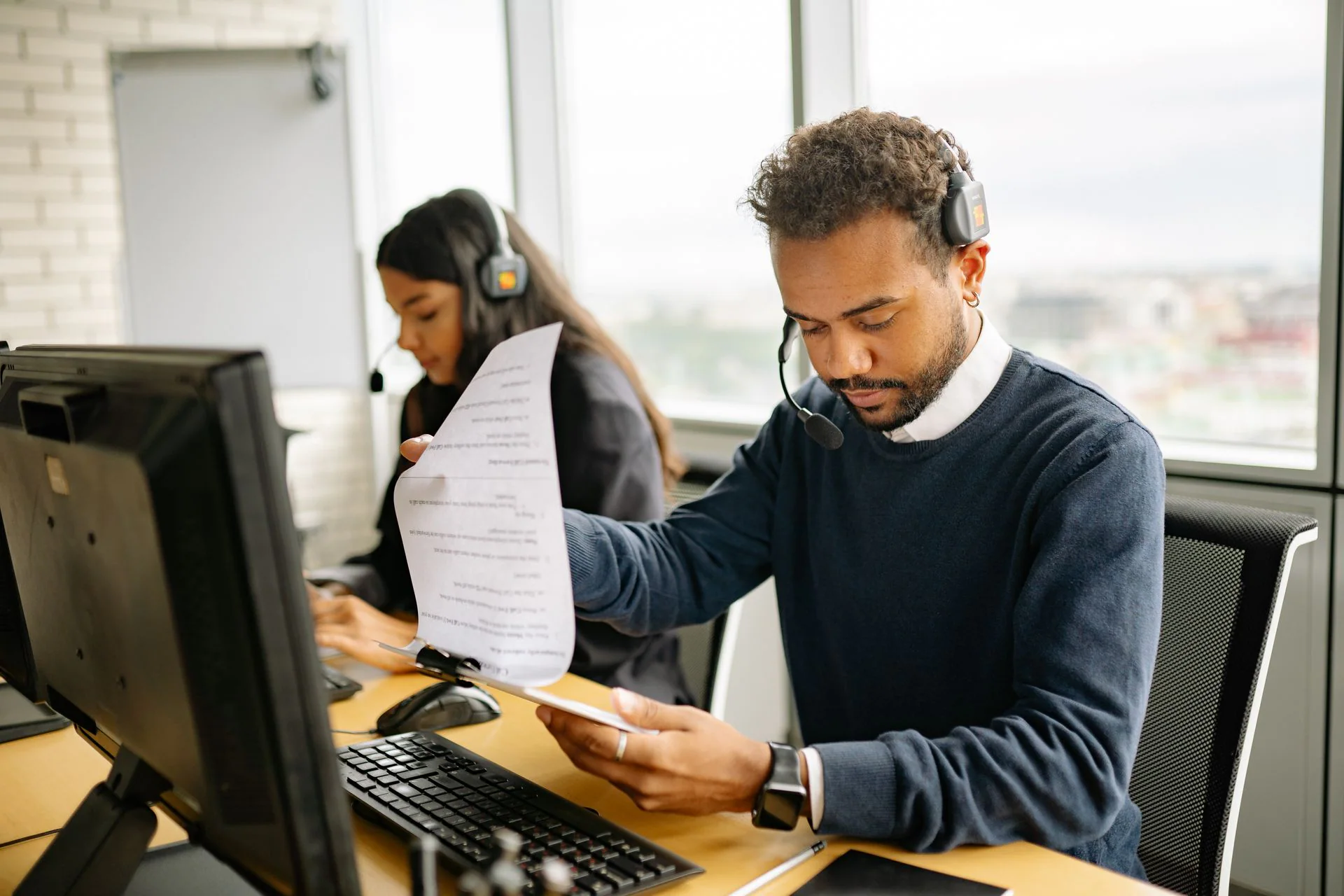 Diverse operations specialists reviewing documents at computer workstations