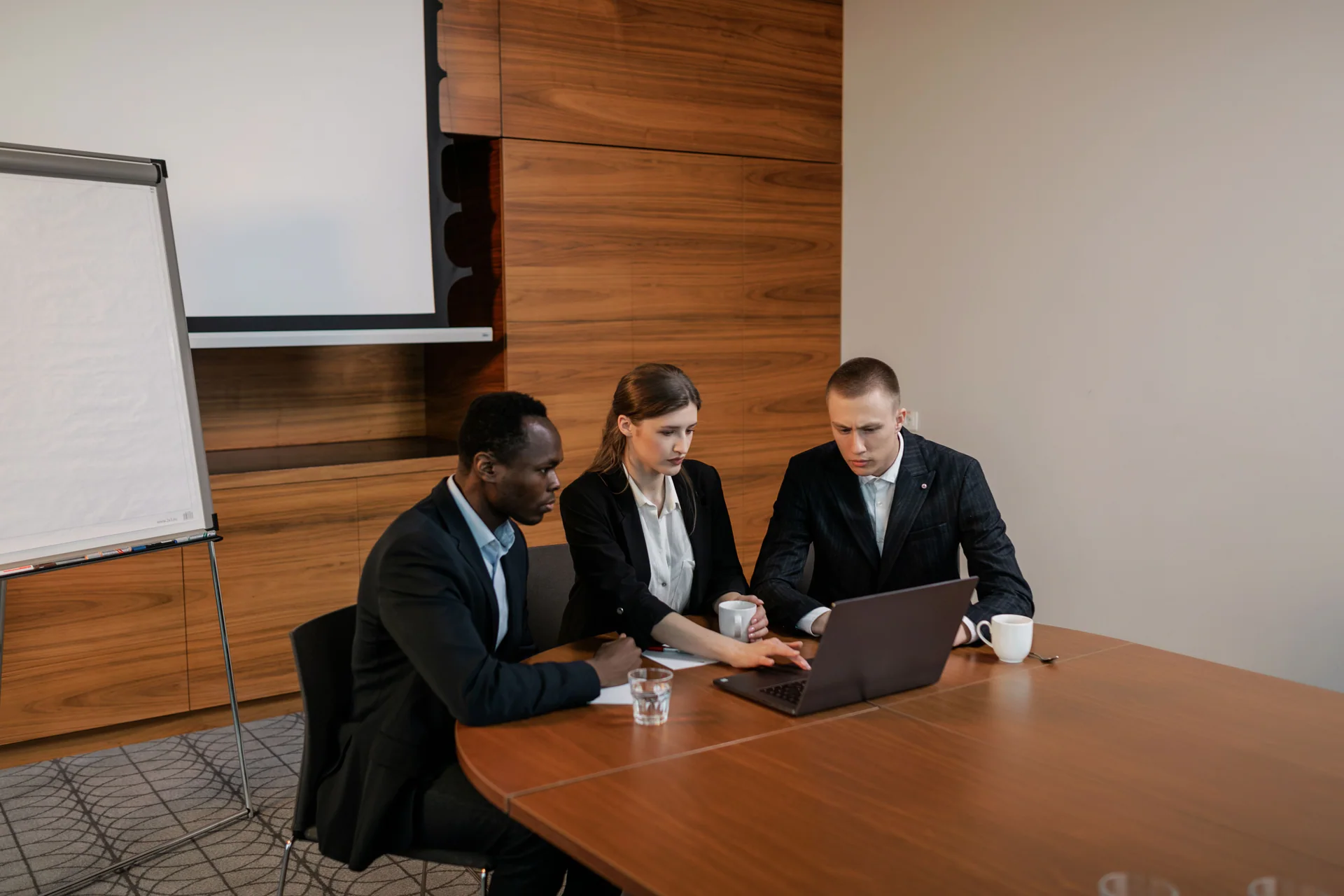 Business professionals collaborating around a laptop in a meeting room