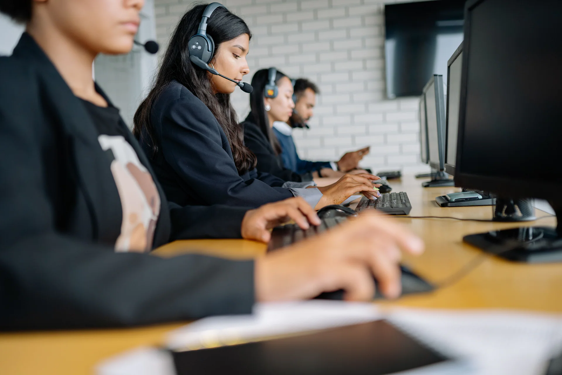 Row of call center agents working at computers with headsets