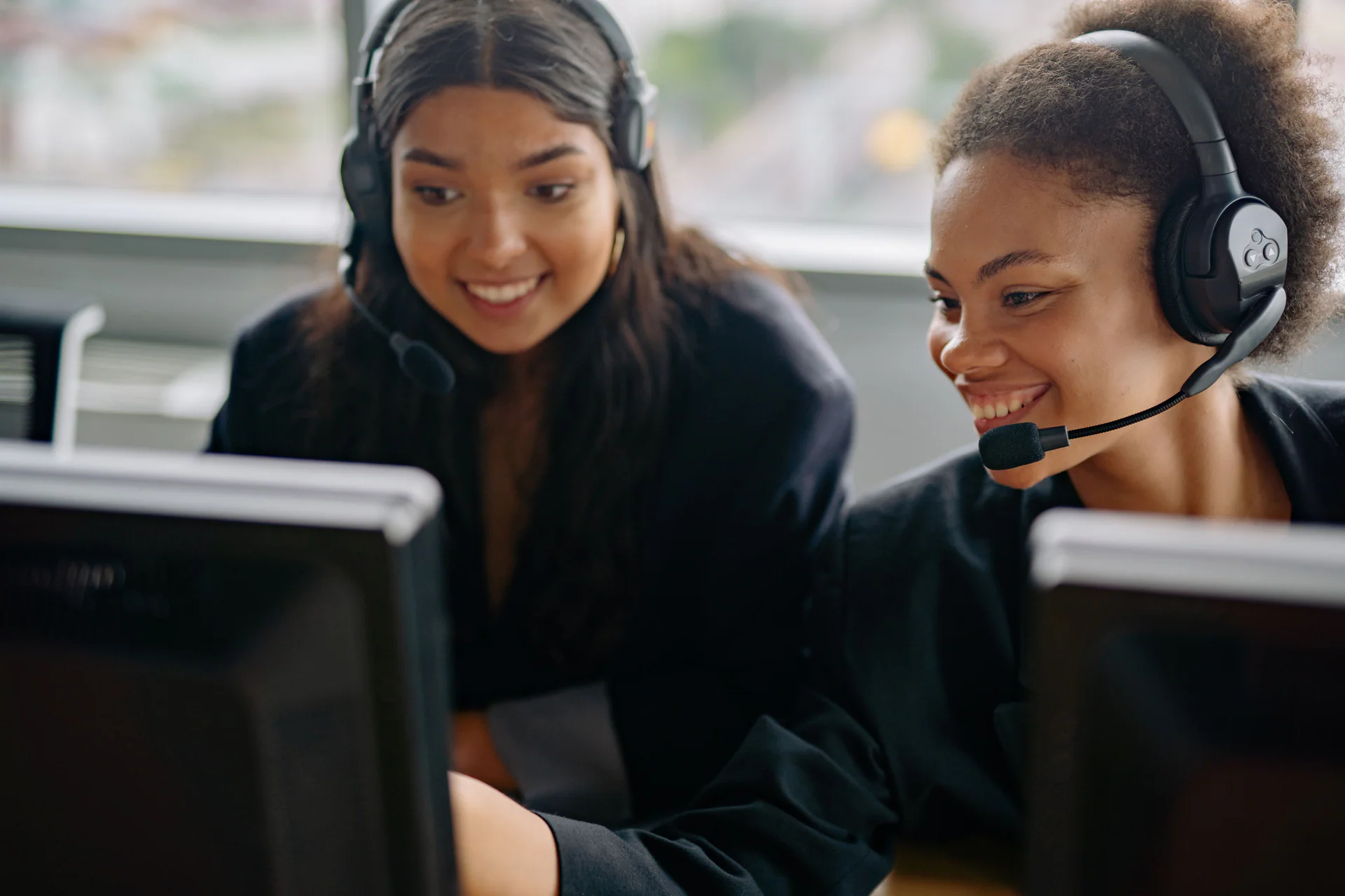 Two support agents wearing headsets while helping customers
